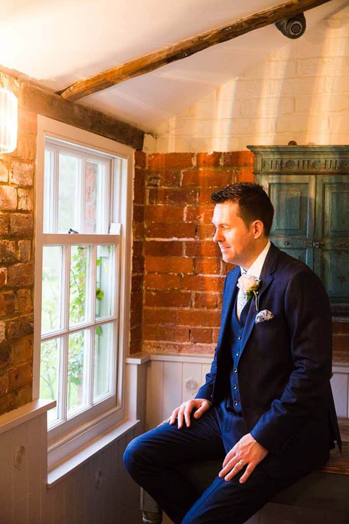 groom-in-navy-suit-portrait-looking-out-of-window