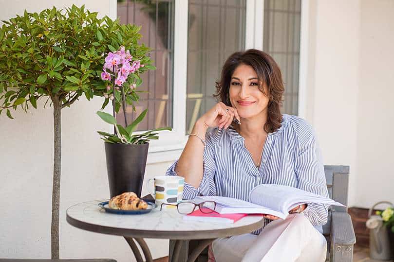 business-portraits-asian-coach-sitting-in-front-porch-garden-with-notepad-open-thinking